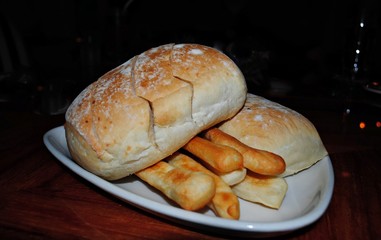 Two buns sliced on top of stick bread served on a small white plate