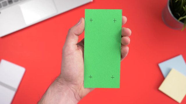 Green screen smartphone being used over a working office desk. Chroma key square screen.