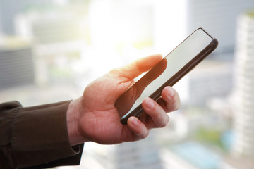 Hand hold smartphone and ligh of sunset as technology and telecommunication concept.