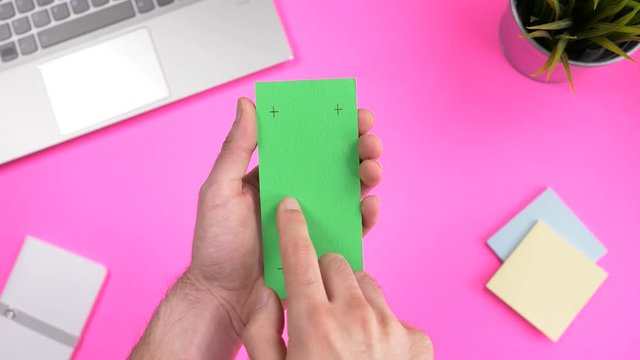 Green screen smartphone being used over a working office desk. Chroma key square screen.