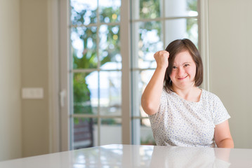 Fototapeta premium Down syndrome woman at home annoyed and frustrated shouting with anger, crazy and yelling with raised hand, anger concept
