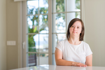 Down syndrome woman at home with serious expression on face. Simple and natural looking at the camera.
