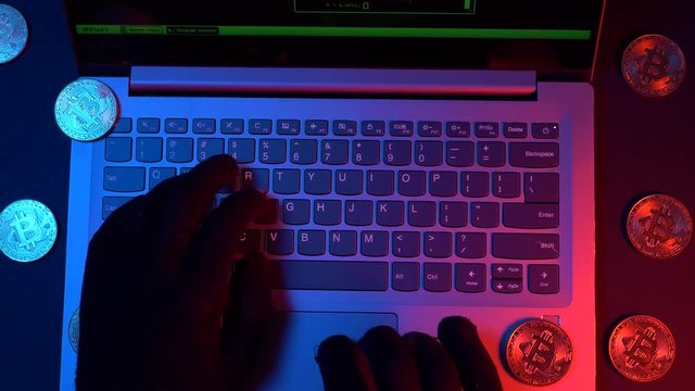 Crypto hacker hacking the system with his computer and bitcoin coins around him.