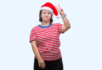 Young adult woman with down syndrome wearing christmas hat over isolated background smiling with happy face winking at the camera doing victory sign. Number two.