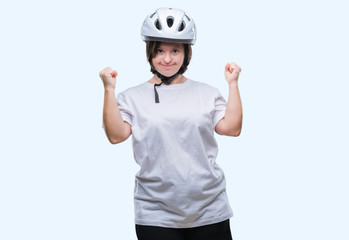 Young adult cyclist woman with down syndrome wearing safety helmet over isolated background very happy and excited doing winner gesture with arms raised, smiling and screaming for success. Celebration