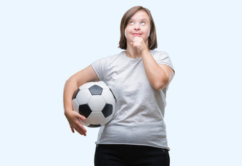 Young adult woman with down syndrome holding soccer football ball over isolated background serious face thinking about question, very confused idea