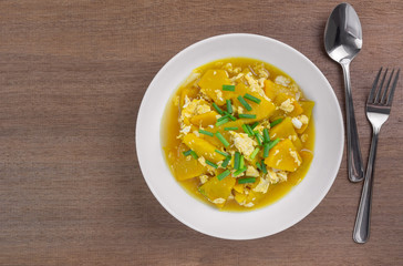 top view of stir fried pumpkin with egg in a ceramic plate on wooden table. delicious and healthy homemade style food concept.
