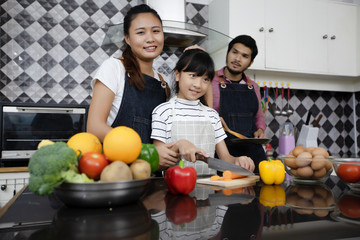 Fototapeta premium Happy Family have Dad, Mom and their little daughter Cooking Together in the Kitchen