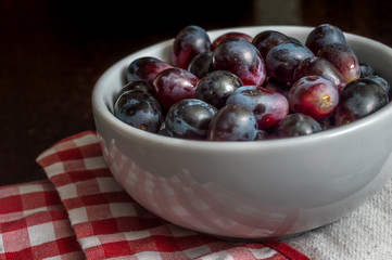 Red grapes in a bowl over a checkered napkin