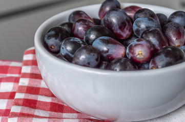 Red grapes in a bowl over a checkered napkin