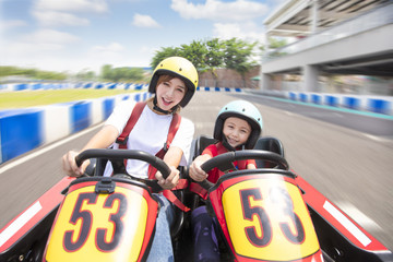 mother and daughter driving go kart on the track - obrazy, fototapety, plakaty