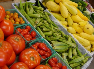 Fresh produce from the farm displayed at the market like red ripe tomatoes, okra, and yellow cucumbers