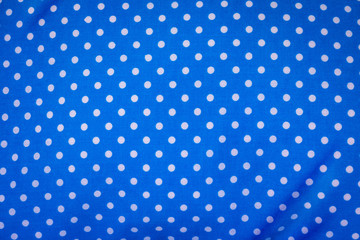 Blue fabric in polka dots pattern background. Modern textile texture. Detail of clothing.