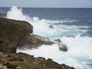 Huge waves splash against sharp rocks in a tropical island