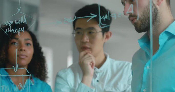 Multi racial team of employees drawing and discussing flowchart diagram in a modern office. 4K UHD 60 FPS SLOW MOTION