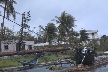 The day after a typhoon hit a tropical island uprooting electric power posts and trees, leaving damaged houses and roads 