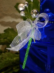 Gift in shiny blue wrapping paper, wide bow and Christmas balls