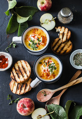 Roasted butternut squash and apples paleo diet vegetarian soup on dark background, top view. Flat lay
