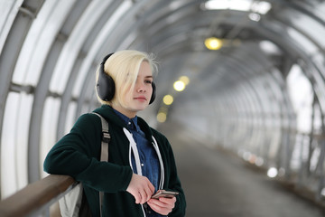 Young girl listens to music in big headphones in the subway