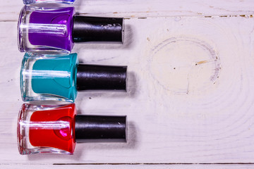 Different nail polishes on a wooden table. Top view