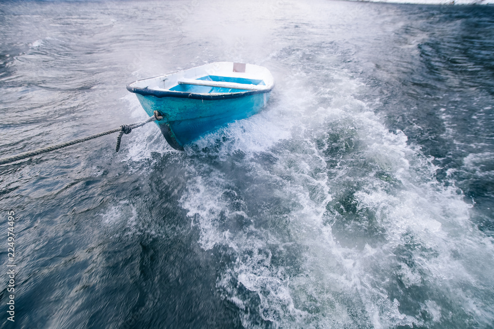 Wall mural Blue boat on a rope in the cold sea