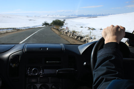 Hand Of Driver Behind The Wheel Of The Right-hand Drive Car. Winter Landscape