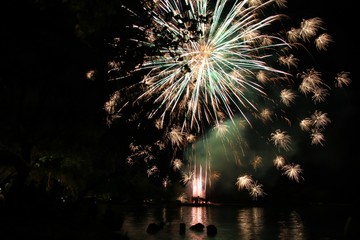 Multiple firework explosion in a dark background, reflected in the sea