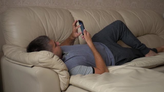 Man using a mobile phone at home on the sofa.