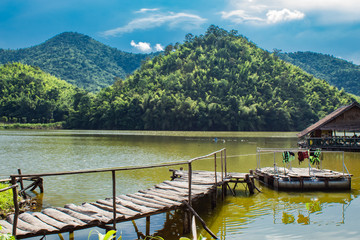 Fototapeta premium The wooden bridge in the reservoir The background of mountains and trees