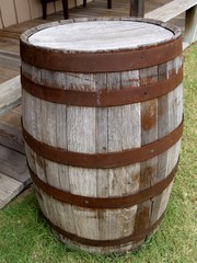 Obraz premium Rustic wooden barrel on a grassy ground, leaning against wooden floors