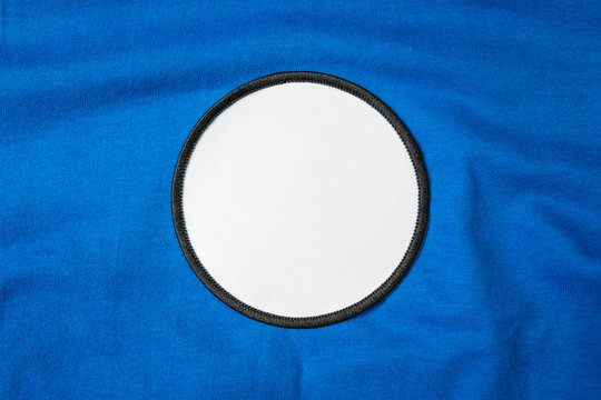 Blank arm patch on blue sport shirt. White team logo and emblem for your montage or edit.