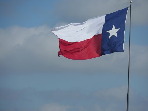 Texas state flag flying in the skies from a pole