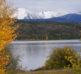 Lake Dillon or Dillon Reservoir bordered by colorful trees and a view of the snow-capped mountains in the distance 