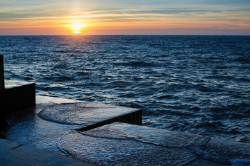 Atlantic sunset at the stone pier in calm weather.