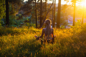 Yoga woman meditating on picturesque glade in a green forest.
