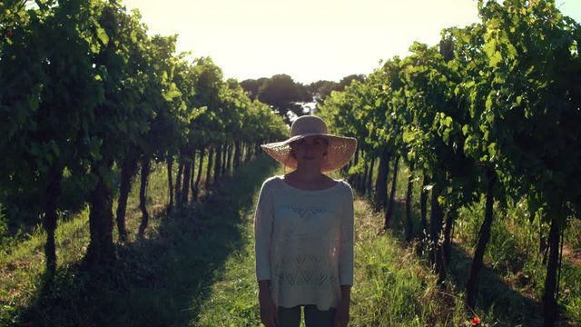 Portrait - Young woman in casual clothing standing in the vineyard at sunset