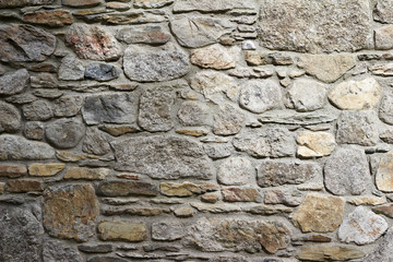 Antique 19th century European stone wall background with stones of varying shapes and sizes, in light gray and brown colors