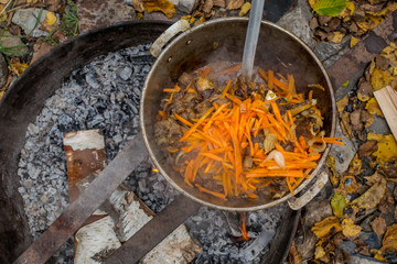 Preparation of pilaf on fire. Carrot cutting. Mix carrots with meat and fat in a saucepan.