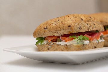 Sandwich with salmon, cheese and cereal bread on white background. Close up.