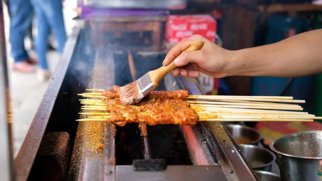 Chef cooking skewered grilled meats in traditional street food in kunming old town, Yunnan, China