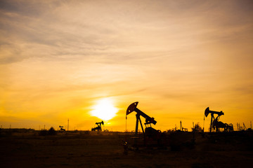 In the evening, the outline of the oil pump. The oil pump, industrial equipment. Oil field site,...
