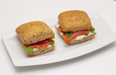 Sandwich with salmon, cheese and cereal bread on white background. Close up.