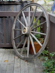 Old wooden wheel of a wagon leaning on a wooden balcony outdoors