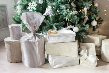 Presents and Gift boxes under Christmas Tree. Beige boxes with ribbon bow. New year decorated house interior. Winter Holiday concept.