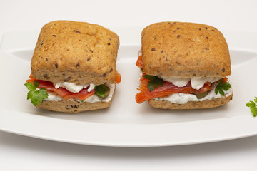 Sandwich with salmon, cheese and cereal bread on white background. Close up.