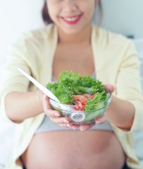 Close up pregnancy woman Holding salad bowl.