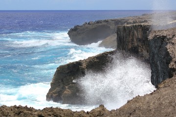 Splashes of waves break against the steep cliffs of the As Matmos Fishing Cliff on Rota, Northern...