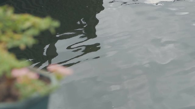 Slow motion of ripple on dark blue water surface with reflection of blue sky and white clouds.