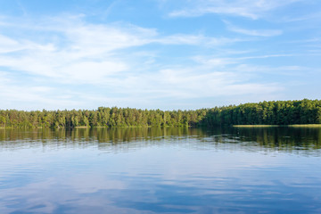 mirror-like surface of the lake against the backdrop of a picturesque blue sky
