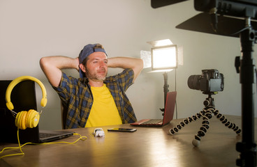 young attractive technology geek man networking with laptop computer recording video blog for...